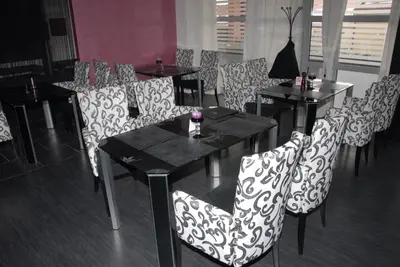 a dining room with black and white chairs and tables at B&B Rose in Vranje