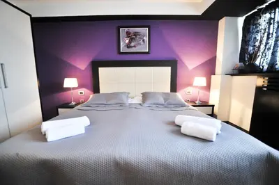 a bedroom with a large bed with purple walls at B&B Rose in Vranje