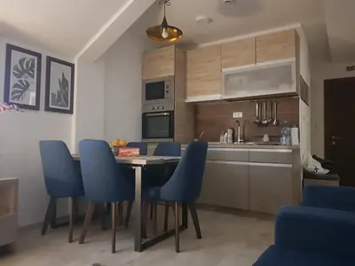 a kitchen with a table and blue chairs in a room at Milmari RELAX apartment in Kopaonik