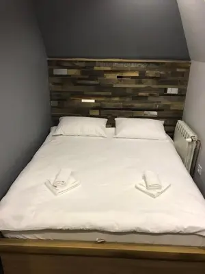 a bed with white sheets and two hats on it at Jules Verne apartments in Kopaonik