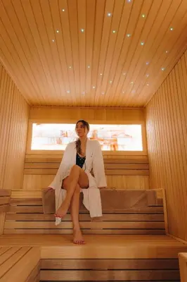 a woman sitting on a bench in a sauna at Privat Studio Milmari in Kopaonik