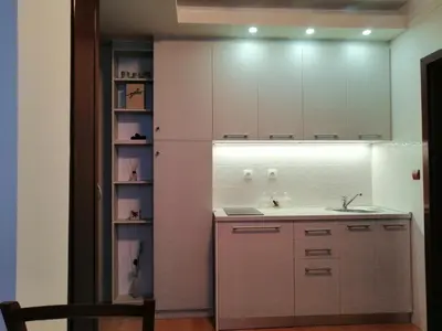 a kitchen with white cabinets and a sink and a shelf at Apartment Lavina Kopaonik in Kopaonik