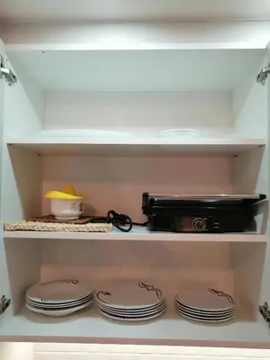 a shelf with plates and a camera in a closet at Apartment Lavina Kopaonik in Kopaonik