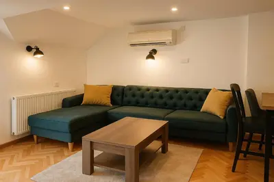 a living room with a green couch and a table at Guest House Vila Pobeda in Vrnjačka Banja