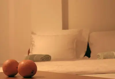 two oranges sitting on a table in front of a bed at Guest House Vila Pobeda in Vrnjačka Banja