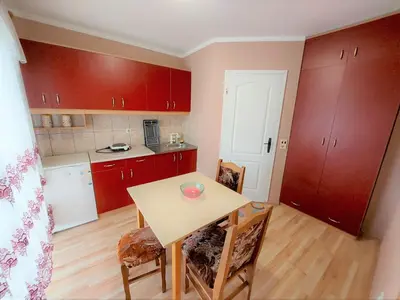 a kitchen with red cabinets and a table and chairs at Apartments Nikolić in Soko Banja