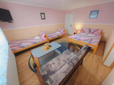 a small room with two beds and a table at Apartments Nikolić in Soko Banja