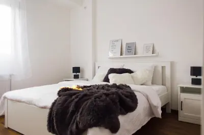 a bedroom with a white bed with a black blanket at NEW Center Apartments in Niš