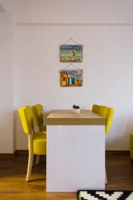 a kitchen with yellow chairs and a white counter at NEW Center Apartments in Niš