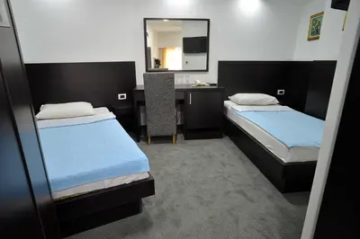 a bedroom with two beds and a desk with a mirror at Hotel Golf in Kruševac