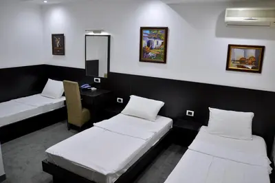 a room with two beds and a desk and a mirror at Hotel Golf in Kruševac