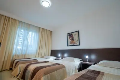 a hotel room with three beds and a window at Hotel Golf Luxury in Kruševac