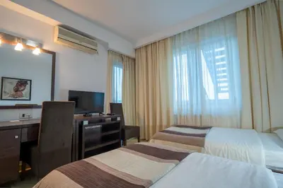 a hotel room with two beds and a desk at Hotel Golf Luxury in Kruševac