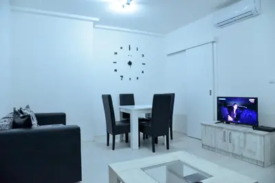 a living room with a table and a clock on the wall at BEST Apartments in Paraćin