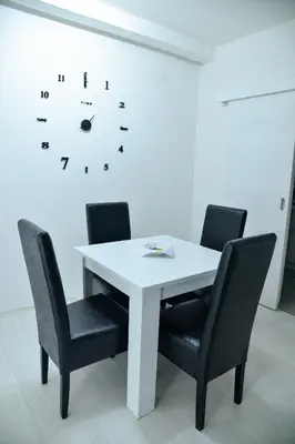 a white table with chairs and a clock on the wall at BEST Apartments in Paraćin