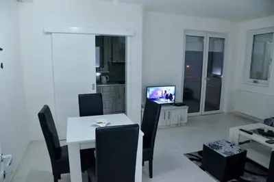 a living room with a white table and chairs and a television at BEST Apartments in Paraćin
