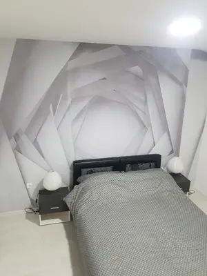 a bedroom with a bed with a geometric wall at BEST Apartments in Paraćin