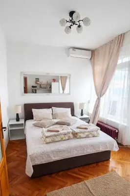 a white bedroom with a large bed and a window at Apartman DUNJA sa terasom in Vranje