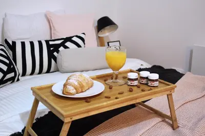 a table with a glass of orange juice and croissants on a bed at Apartment Take a breath in Vrnjačka Banja
