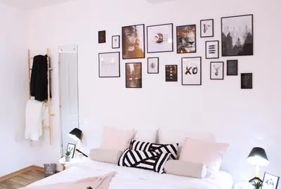 a white bedroom with a white couch and pictures on the wall at Apartment Take a breath in Vrnjačka Banja