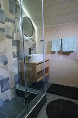 a bathroom with a shower with a sink and a mirror at Sunrise Apartments in Niš