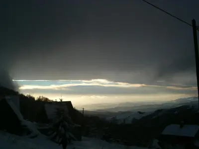 a view of a snowy mountain with the sun in the sky at Villa Kostic Kopaonik in Kopaonik