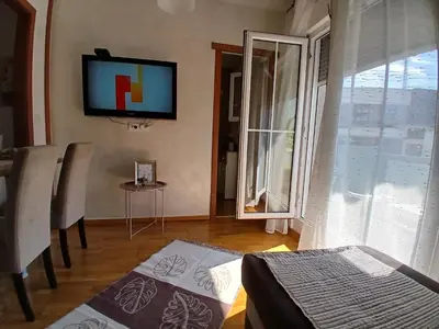a living room with a tv on the wall and a table at Apartman Jovanović in Vrnjačka Banja