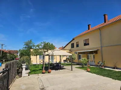 a house with a patio with an umbrella at Apartments Kuca Aleksic in Niš