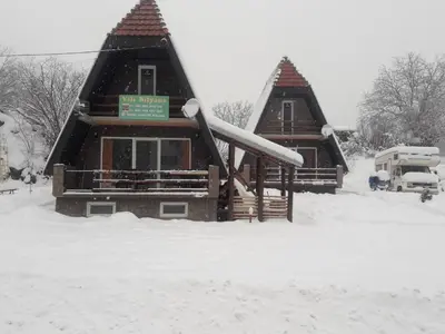 a couple of log homes in the snow at Vili Bilyana in Crni Vrh