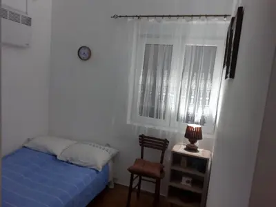 a bedroom with a bed and a window and a chair at Apartman Krstić in Vrnjačka Banja
