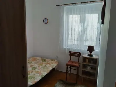 a bedroom with a bed and a chair and a window at Apartman Krstić in Vrnjačka Banja
