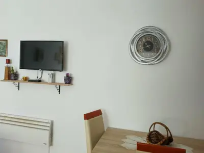 a clock on the wall above a table with a tv at Apartman Krstić in Vrnjačka Banja