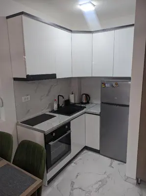a kitchen with white cabinets and a stainless steel refrigerator at Sokobanja Apartmani in Soko Banja