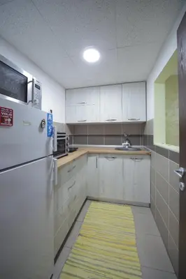 a kitchen with white cabinets and a sink and a refrigerator at Apartman DIAMOND-LUX in Jagodina