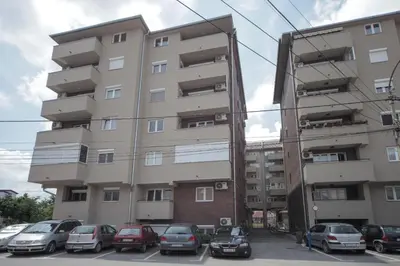 a tall building with cars parked in a parking lot at Apartman DIAMOND-LUX in Jagodina