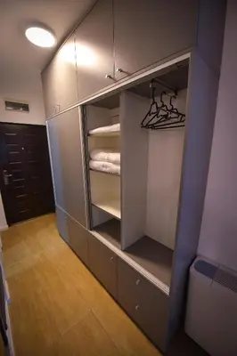 a walk in closet with white cabinets and a door at Urban Apartment in Niš