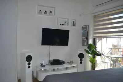 a bedroom with a flat screen tv on a white wall at Urban Apartment in Niš
