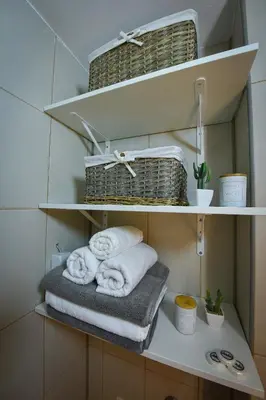 a shelf with towels and baskets in a bathroom at Urban Apartment in Niš