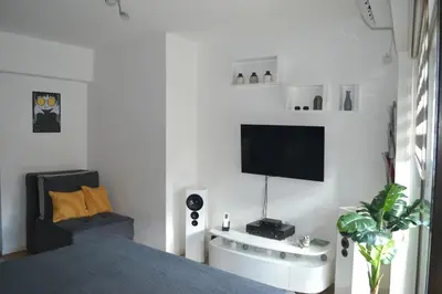 a bedroom with a bed and a tv on a wall at Urban Apartment in Niš