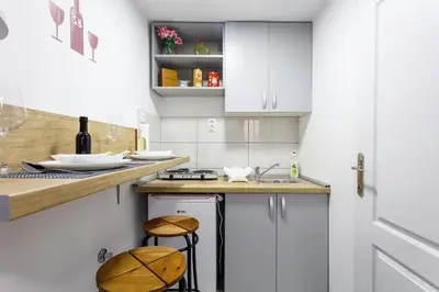 a kitchen with white cabinets and a counter with stools at SB centar apartmani in Niš