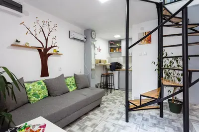 a living room with a couch and a tree on the wall at SB centar apartmani in Niš