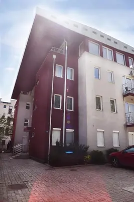 a red building with the sun shining on it at Apartment Matovic in Vrnjačka Banja