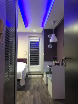 a bedroom with purple lighting and a bed and a sink at Vladana LUX App in Kruševac
