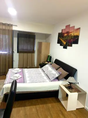 a bedroom with a bed and a table with a lamp at Laguna apartman 2 in Niš