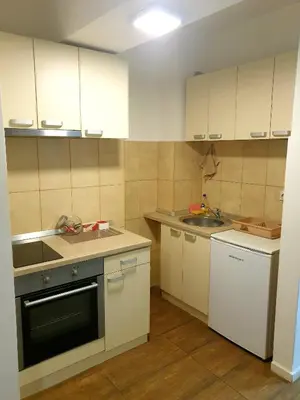 a small kitchen with white cabinets and a sink at Laguna apartman 2 in Niš