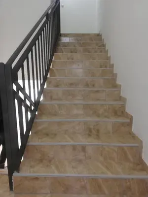 a staircase with wood floors and a black railing at Laguna apartman 2 in Niš