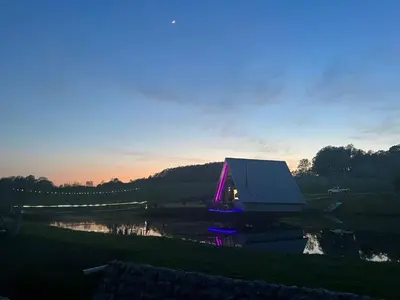 a house sitting on top of a field next to a lake at Resavsko Etno Selo in Despotovac