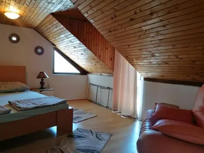 a attic room with a bed and a couch at Apartman Kaća in Vrnjačka Banja