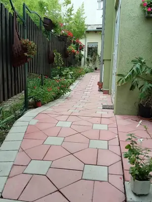 a pink tile walkway with a fence and flowers at Apartman Kaća in Vrnjačka Banja