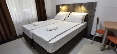 a bedroom with a large bed with white sheets and pillows at Apartments Banjica in Soko Banja